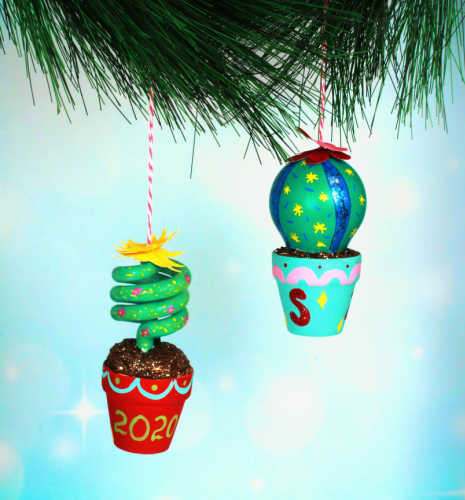 Two cacti ornaments made from recycled lightbulbs hang off of a Christmas tree.